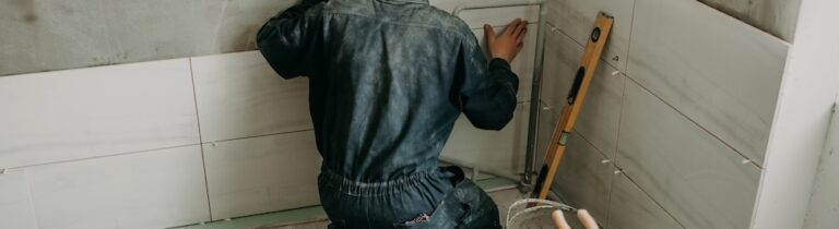Worker puts large ceramic tiles on the walls in bathroom